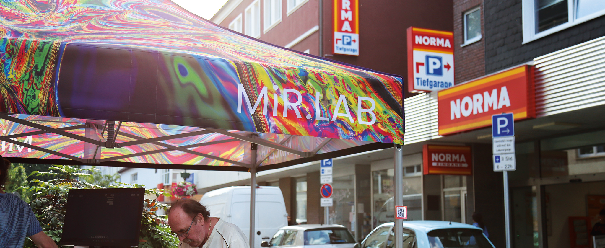 Ein Pavillon mit der Aufschrift "MiR.LAB" neben einer Filiale des Supermarktes "Norma".