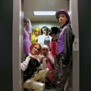 Eine Gruppe Drag-Artists posiert in einem Aufzug.