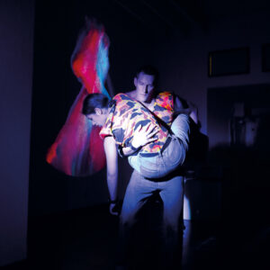 Eine Person trägt eine andere vor einer Projektion.