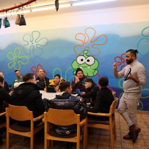 Mann erklärt Jugendlichen etwas auf einem Ipad bei dem Gaming-Workshop Cyberflöte