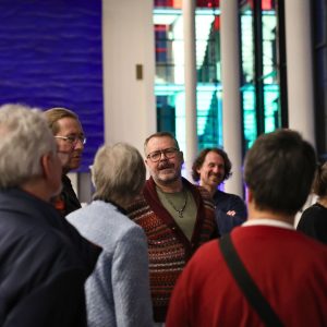 Auf dem Bild stehen ganz viele Menschen in einem Raum.
