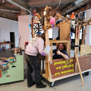 Auf dem Bild sind drei Menschen zu erkennen die in einer Werkstatt an einem Wagen Projekt Arbeiten.