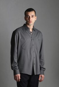 Portraitfoto Hamidreza, Dunkle kurze Haare, graues Hemd, schwarze Hose, grauer Hintergrund